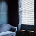 white venetian window blind covering a window in a dark blue room