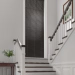 dark brown wooden venetian window blinds covering a large window on a landing of a staircase